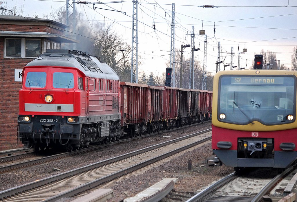 232 358-2 kommt mit einem Ganzzug offener G�terwagen aus Richtung Oranienburg das Karower Kreuz Berlin hochgefahren  Richtung Bernau und �berholt eine S2 der Berlin S-Bahn bei der Einfahrt im S-Bhf. Berlin-Karow, 28.03.11
