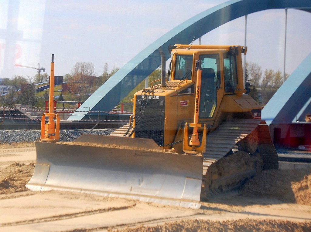 Bild durchs S-Bahnfenster, eine gro�e CAT D6N Raupe (Leasingbaumaschine) an der Bahnbaustrecke N�he Berlin-Adlershof, 24.04.10