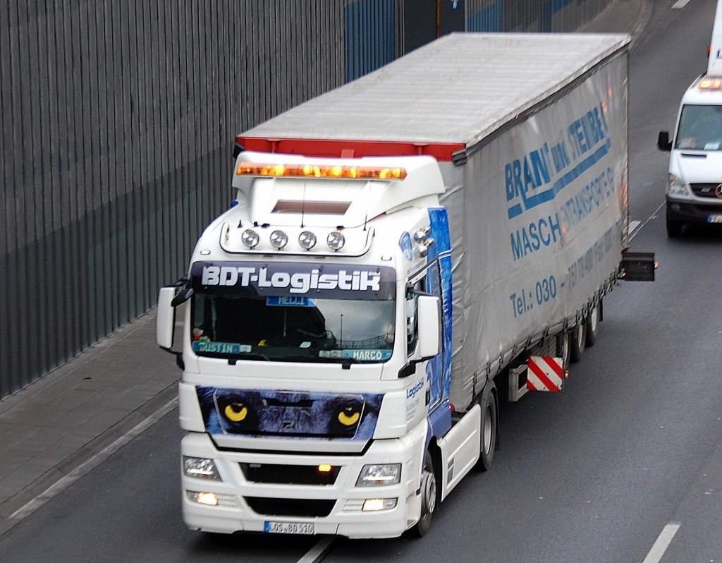 Dieser MAN Sattelzug der Sped. BDT Logistik hatte �berbreite und daher sogar Warnlicht und Begleitfahrzeug dabei, man erkennt das �berbreite Ladegut (Maschine oder Maschinenteil) unter der Plane, 10.01.12 Berliner Stadtautobahn H�he Kaiserdamm.