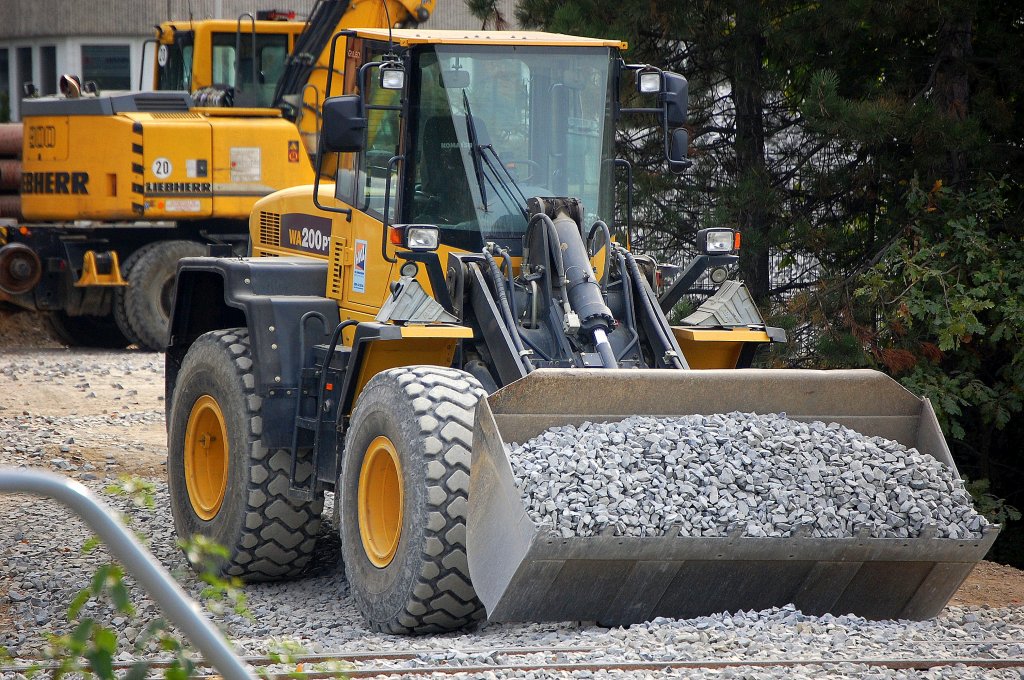 Diesmal ist ein KOMATSU WA200PT HKL-Leasingbagger am Bhf. Berlin-Sch�nefeld Flughafen t�tig, hier mit Gleisschotter in der Schaufel, 09.10.10