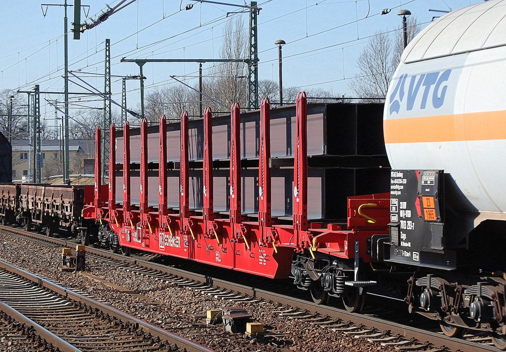 Drehgestellflachwagen mit vier Rads�tzen mit Rungen mit Niederbindeeinrichtung von DB SCHENKER mit schweren Stahltr�gern beladen, Wagentyp leider nicht genau erkannt wahrscheinlich ein Rbns 641, 08.03.11 Bhf. Flughafen Berlin-Sch�nefeld.