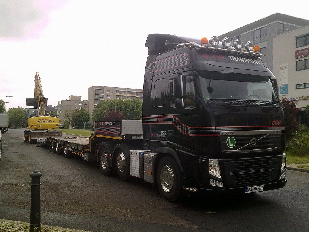 Eine OKO TRANSPORT VOLVO FH 500 3 Achs Zugmaschine mit Sattelbr�cke l�dt einen NEW HOLLAND Mobilbagger ab, 23.05.13 Berlin-Pankow.
