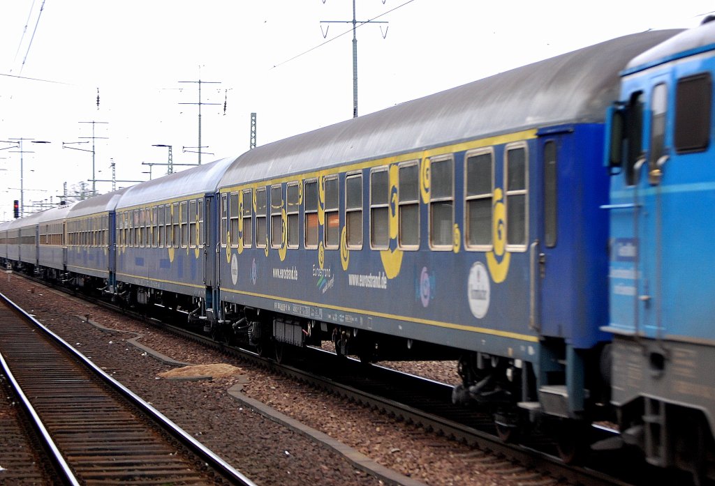 Schon seit l�ngerer Zeit hat der Reise- und Eventveranstalter EUROTRAIN (ET) diese ehemaligen DB Personenwagen in dunkelblau mit gelben Kreisen + Eurotrain Logo + Krombacher Werbung im Einsatz, hier am 12.01.12 in einem Sonderzug gezogen von 1042 520-8 der Centralbahn AG Durchfahrt Bhf.Flughafen Berlin-Sch�nefeld. 