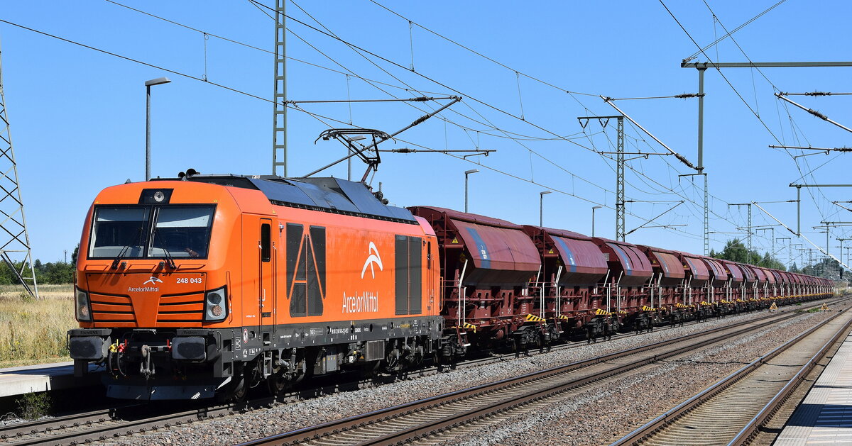 AMEH Trans - ArcelorMittal Eisenhüttenstadt Transport GmbH, Eisenhüttenstadt [D] mit ihrer Vectron Dual Lok  248 043  [NVR-Nummer: 90 80 2248 043-2 D-EKO] und einem Ganzzug polnischer Schüttgutwagen mit Schwenkdach am 01.07.25 Höhe Bahnhof Rodleben.
