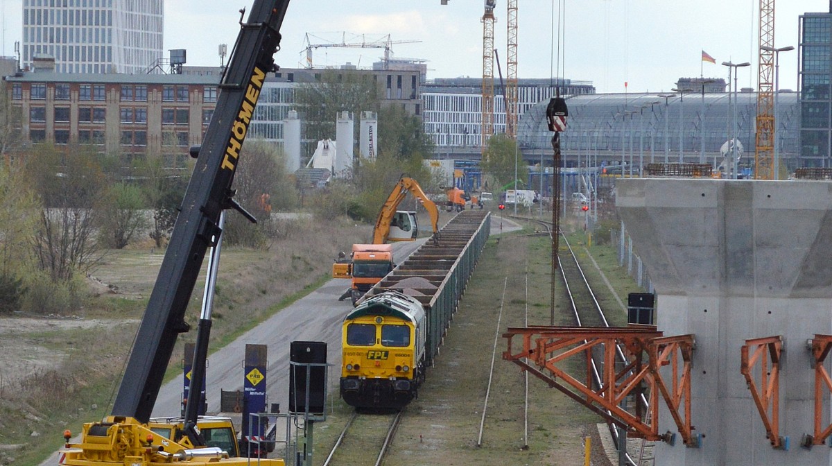 Auf der Großbaustelle zum Neubau der S-Bahnlinie S21 ab Berlin Hbf. liefert schon seit einiger Zeit die polnische FPL, hier mit der Lok 66004, Kies in langen Ganzzügen, die dann direkt vor Ort von einem Umschlagbagger in bereitstehende Sattelkipper umgefüllt werden, 22.04.15 Berlin Wedding/Moabit.