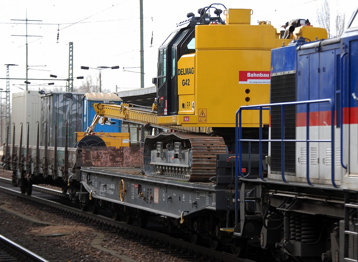 Das Raupenrammgerät DELMAG G42 der DB Bahnbau Gruppe uf einem Drehgestell-Flachwagen + weitere Baucontainer auf einem weiteren Wagen am 28.11.13 Bhf. Flughafen Berlin-Schönefeld. 
