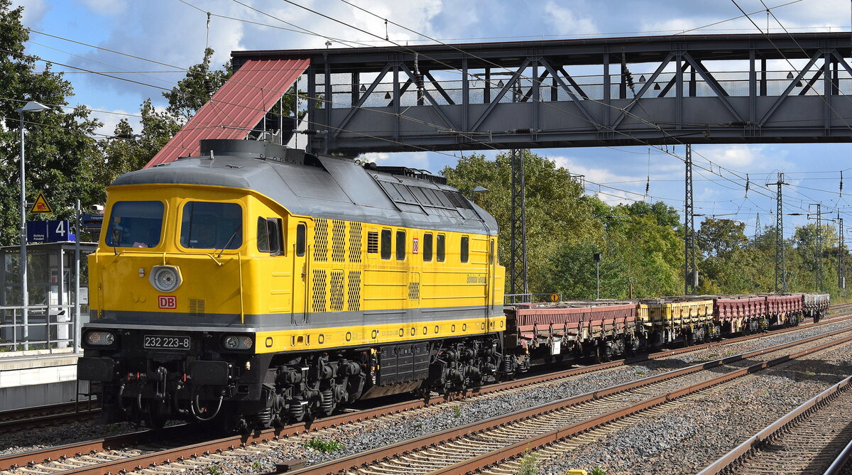 DB Bahnbau Gruppe GmbH, Berlin mit ihrer  232 223-8  (NVR:  92 801232 223-8 D-DBBBG ) und einigen Drehgestell-Flachwagen (leer) am 29.09.25 Höhe Bahnhof Saarmund.