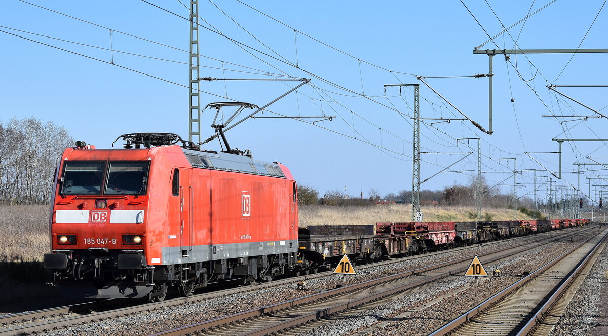 DB Cargo AG, Mainz [D] mit ihrer  185 047-8  [NVR-Nummer: 91 80 6185 047-8 D-DB] mit einem gemischten Güterzug unterschiedlicher Drehgestell-Flachwagen (leer) am 20.03.25 Höhe Bahnhof Rodleben.