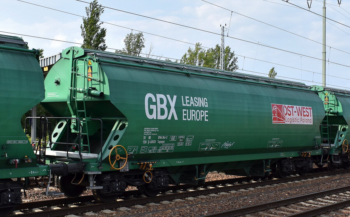 Ein Drehgestell-Schüttgutwagen mit Schwenkdach und dosierbarer Schwerkraftentladung für Getreidetransporte vom Einsteller GREENBRIER LEASING EUROPE BV mit der Nr. 37 TEN 80 D-GBXEU 0764 244-2 Tagnpps (GE) vermietet siehe Firmenlogo am Wagen an das polnische Unternehmen Ost-West Logistic Poland Sp. z o.o. in einem Getreidezug am 18.06.25 Höhe Bahnhof Schönefeld b. Berlin.