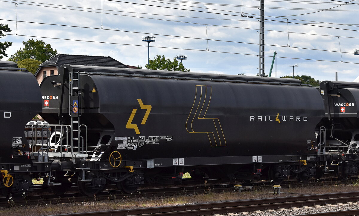 Ein Drehgestell-Schüttgutwagen mit Schwenkdach und dosierbarer Schwerkraftentladung für Getreidetransporte vom Einsteller WASCOSA AG mit deutscher Registrierung mit er Nr. 33 TEN 80 D-WASCO 0764 967-0  Tagnpps (GE) vermietet an das Logistikunternehmen Rail4ward siehe Wagendesign in einem Ganzzug (Getreidezug) am 10.07.25 Höhe Bahnhof Magdeburg Hbf.