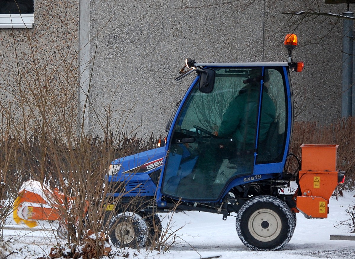 Ein kleiner Diesel-Gartentraktor, ein ISEKI SXG 19 mit Kehrbürste und Streutrichter am Heck beim Schneeräumdienst, 22.01.14 Berlin-Pankow. 