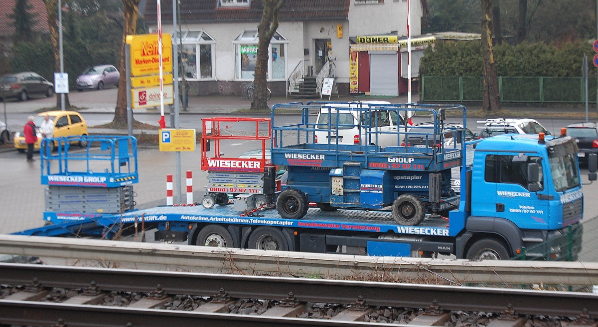 Ein MAN TGA 26.350 Lade-LKW der Vermietfirma WIESECKER lädt mobile Teleskoparbeitbühnen ab, 17.01.14 Berlin-Karow.