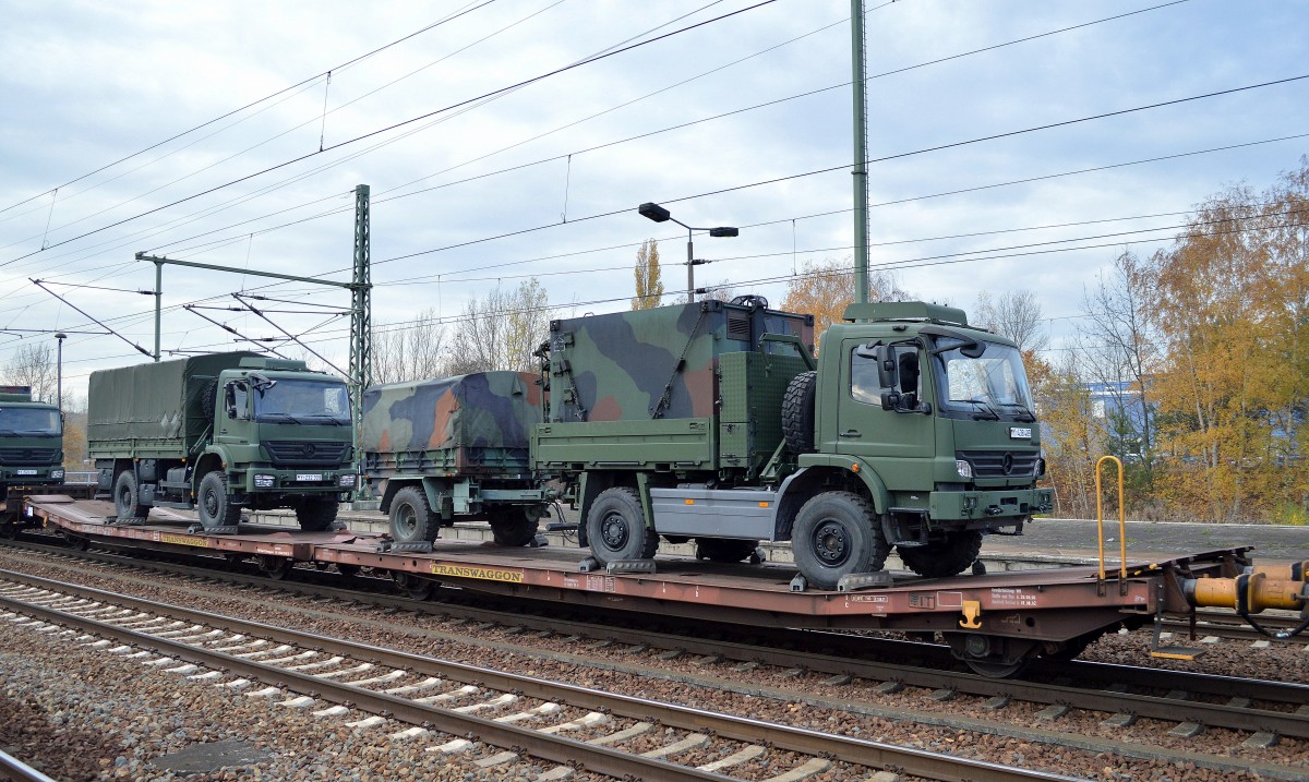 Flachwageneinheit mit abgesenktem Fußboden vom Einsteller TRANSWAGGON mit der Nr. 23 RIV 80 D-TWA 4313 473-9 Laads 800 B belanden mit zwei LKW der Bundeswehr, vorne ein MB Atego 1018A (Lkw 2t hümS (BW)) mit Hänger und dahinter ein MB Axor 1829A (Lkw 5t hümS (BW)) am 05.11.15 in einem Militärtransportzug im Bhf. Flughafen Berlin-Schönefeld. 