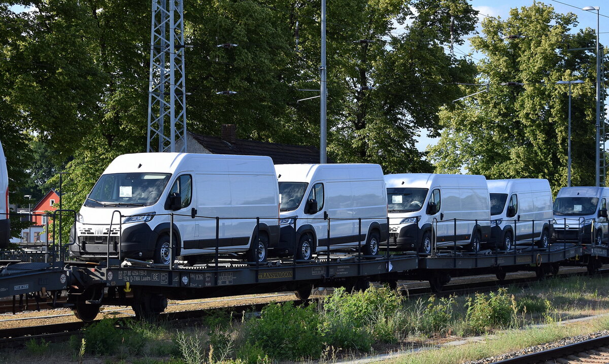 Flachwageneinheiten mit mit abgesenktem Fußboden und Radvorlegern vom Einsteller TRANSWAGGON mit der Nr. 27 TEN 80 D-TWA 4354 159-0 Laadrs (GE) beladen mit fabrikneuen FIAT DUCATO Transportern in einem Transportzug am 19.06.25 Höhe Bahnhof Ruhland.
