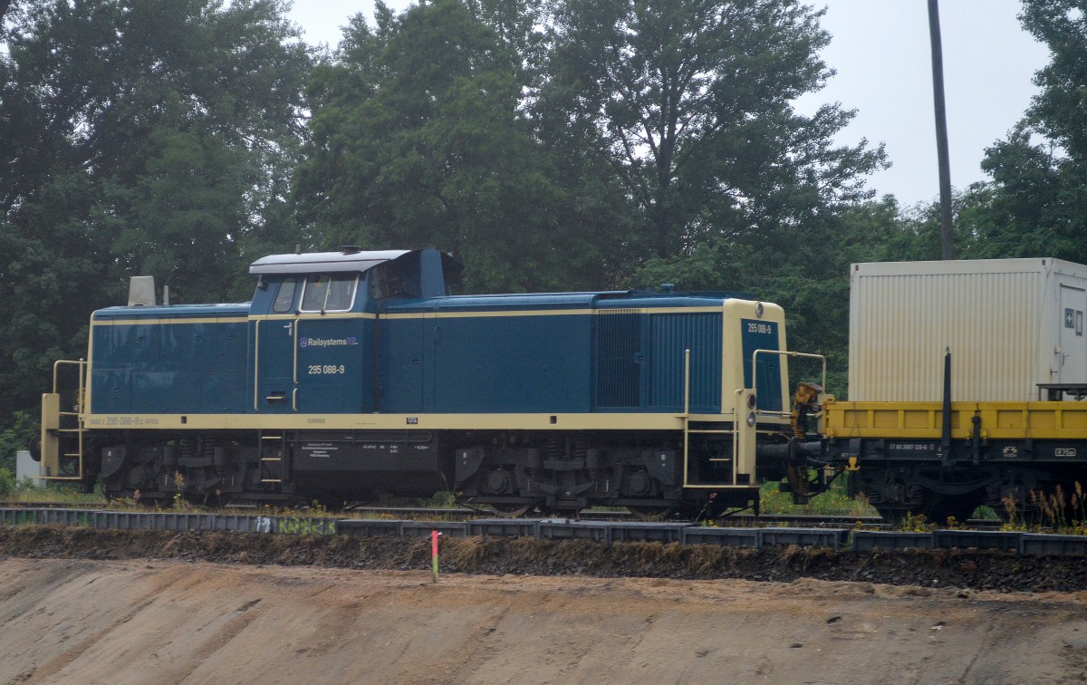 Für ein Fensterbild aus der S-Bahn + grauem Wetter mit Nieselregen ganz ok! Railsystems RP 295 088-9 mit einigen Drehgestell-Flachwagen mit Baucontainern und Kabelrollen mal wieder Berlin-Schönweide im Einsatz, an einigen Abschnitten zwischen Baumschulenweg und Treptow hängt inzwischen schon die Oberleitung wieder, 14.07.15