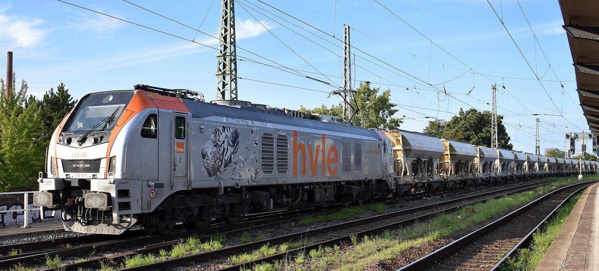 Havelländische Eisenbahn AG, Berlin-Spandau [D] mit ihrer Eurodual Lok  159 010  [NVR-Nummer: 90 80 2159 010-8 D-HVLE] und einem Baustoff-Transportzug (Sand) am 07.08.25 Höhe Bahnhof Magdeburg-Neustadt.
