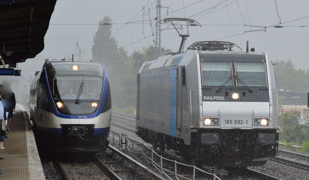 HSL mit der Railpool-Lok 185 692-1 fährt gerade an dem NEB Triebzug VT 734 der Linie RB27 Wandlitzsee vorbei der im Bf. Berlin-Karow einfährt bei sintflutartigem Regen am 29.06.17