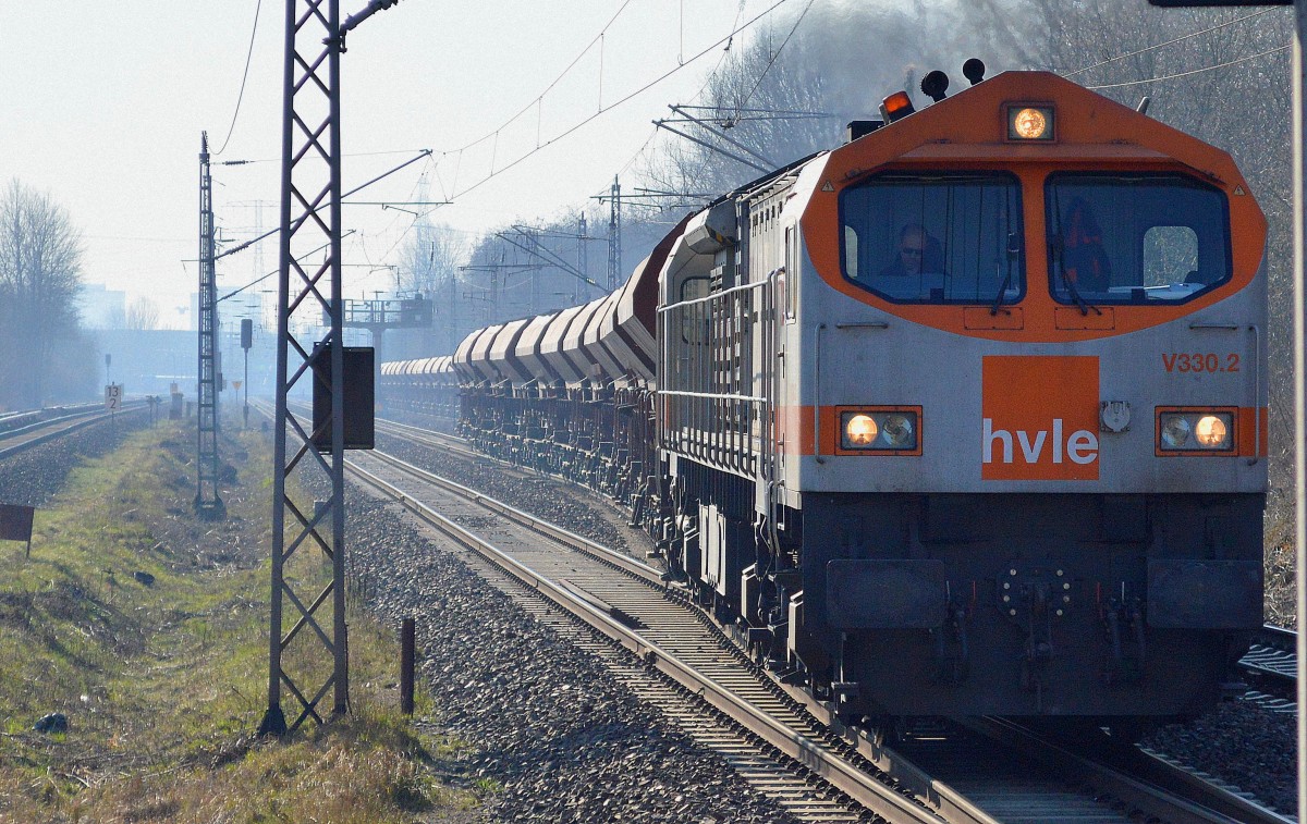 Orange Tiger hvle V330.2 (250 010-6) verlässt mit einem wirklich langen Ganzzug Schüttgutwagen am frühen Morgen das Industrieübergabegebiet Berlin-Nordost am 19.03.15 Berlin-Hohenschönhausen. 