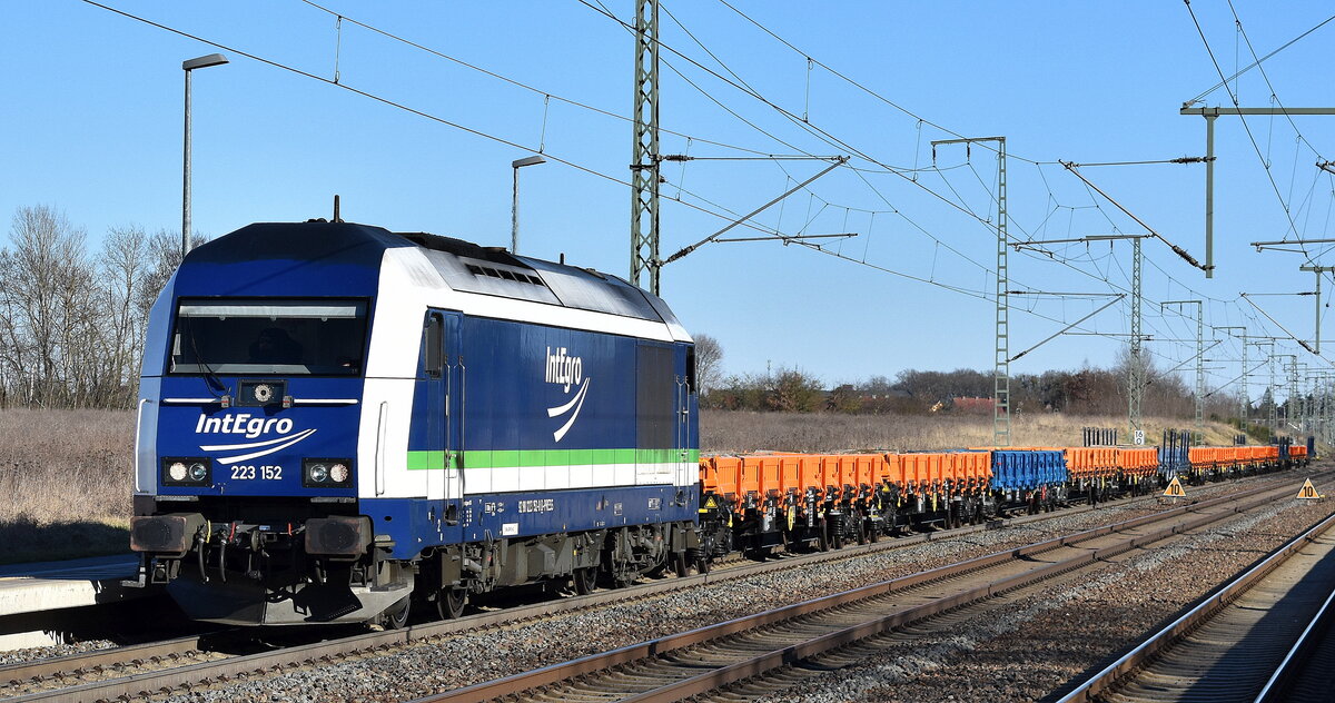 PRESS/IntEgro Verkehr GmbH, Neuenmarkt mit ihrer  223 152  (NVR:  92 80 1223 152-0 D-PRESS ) und einem Ganzzug Drehgestell-Flachwagen mit alten Beton-Gleisbohlen beladen am 18.03.25 Höhe Bahnhof Rodleben.