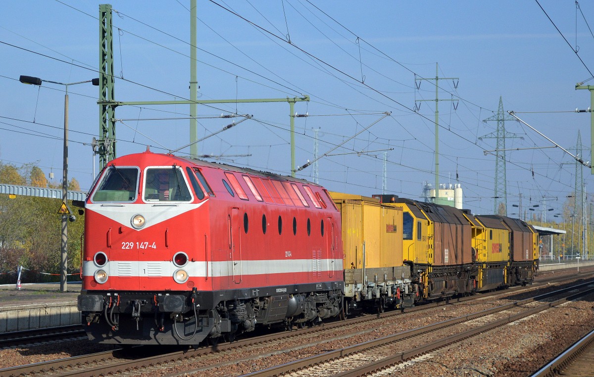 Seit September 2015 neu nun wieder in orientrot-weißer Farbe im Besitz der Fa. CLR, 229 147-4 mit dem Schienenschleifzug RG 48 II der Fa. Schweerbau am Haken am 31.10.15 bei der Durchfahrt Bhf. Flughafen Berlin-Schönefeld.