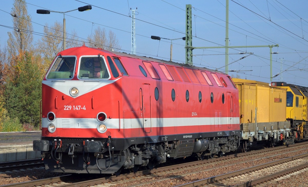 Seit September 2015 neu nun wieder in orientrot-weißer Farbe im Besitz der Fa. CLR, 229 147-4 mit dem Schienenschleifzug RG 48 II der Fa. Schweerbau am Haken am 31.10.15 bei der Durchfahrt Bhf. Flughafen Berlin-Schönefeld.