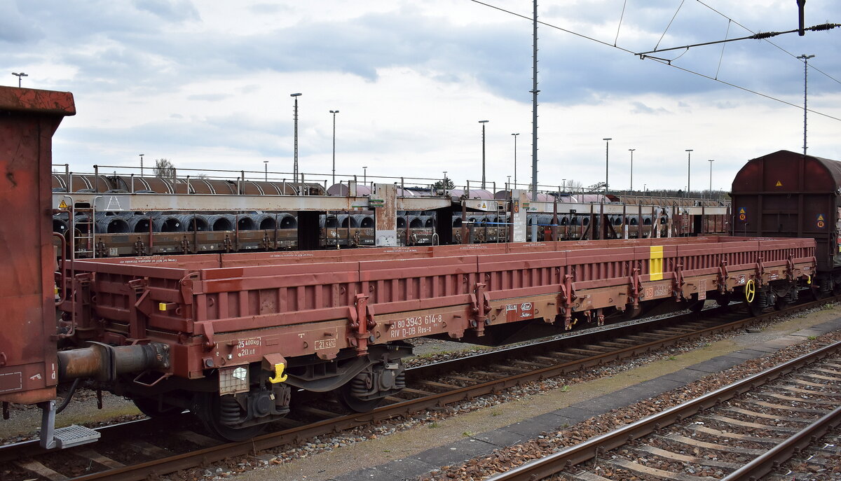 Vierachsiger Flachwagen der Gattung Res-x 679.1 der DB Cargo (der markante gelbe Strich in der Mitte des Wagens ist ein Zeichen das er für den Bauzugdienstdient zum Einsatz kommt) zum Transport von schweren Schüttgütern mit der Nr. 31 RIV 80 D-DB 3943 614-8 Res-x 679.1 in einer gemischten Abstellgruppe Rbf. Seddin am 09.04.25