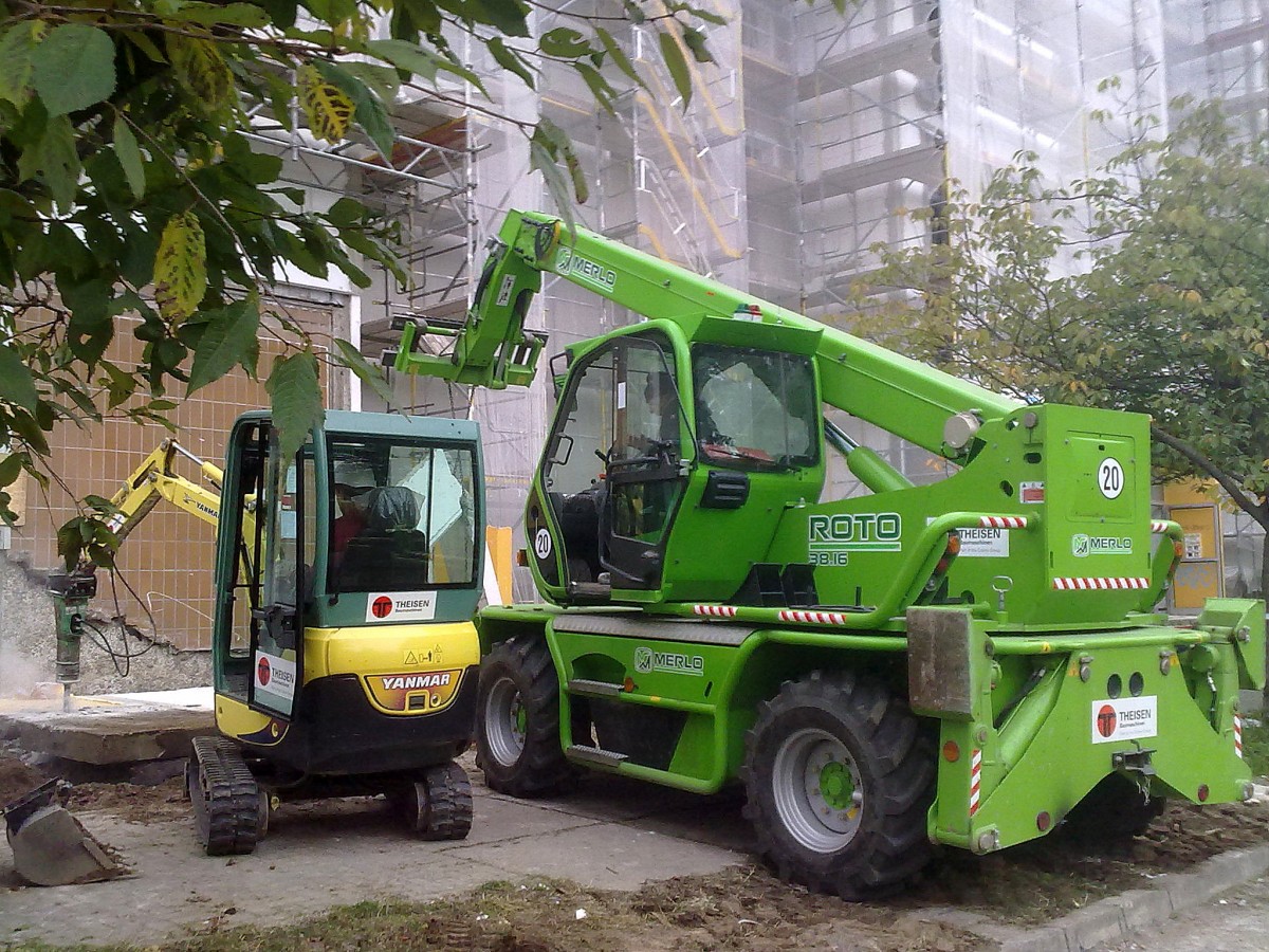Zwei Mietbaumaschinen im Einsatz, ein MERLO ROTO 38.16.und ein kleiner AMMANN YANMAR SV 17 EX am 10.10.13 Berlin-Pankow beim Abri� von alten Betonplatten einer Engangshalle.