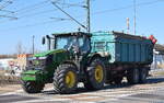 Ein JOHN DEERE 7230 R Traktor mit Hänger mit Abrollmulde am 20.03.25 Höhe Bahnübergang Bahnhof Rodleben. 